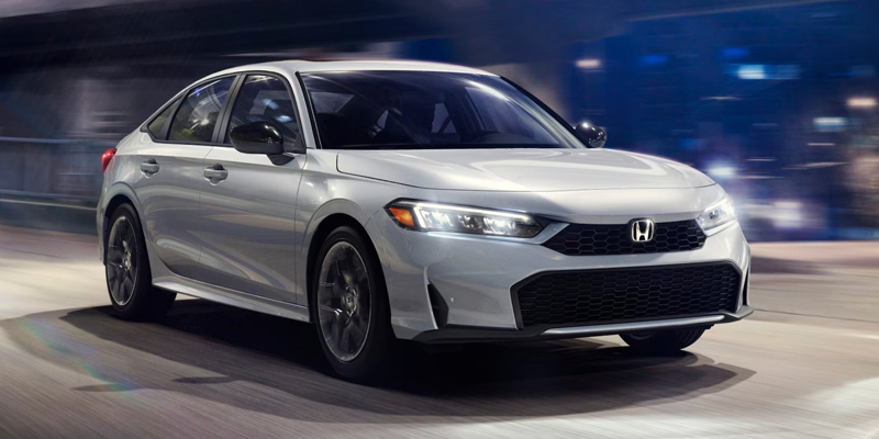 White Honda Civic driving through a city at night.