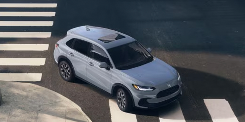 White SUV driving through a city intersection from an aerial view.