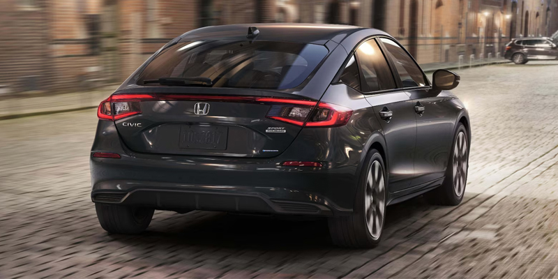 Dark gray Honda Civic sedan driving on a city street.